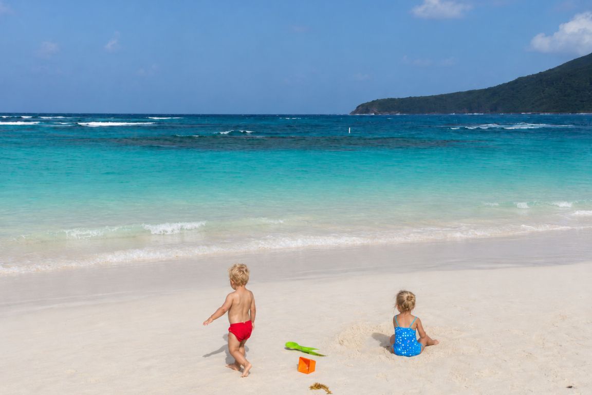 Kids enjoying the soft white sand and crystal-clear waters of Flamenco Beach during a guided island adventure with Culebra Tours